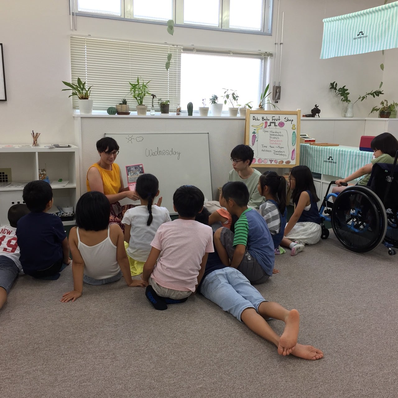 ホワイトボードの前で先生のお話を囲んで聞く小学生たち