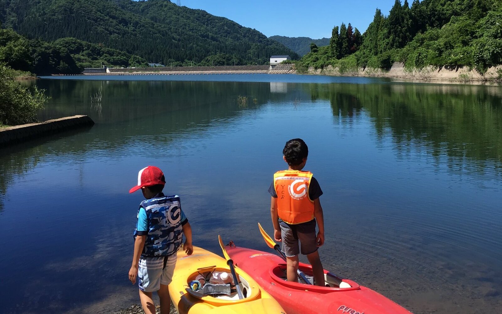 夏の湖でカヤックに乗り出す子どもたち